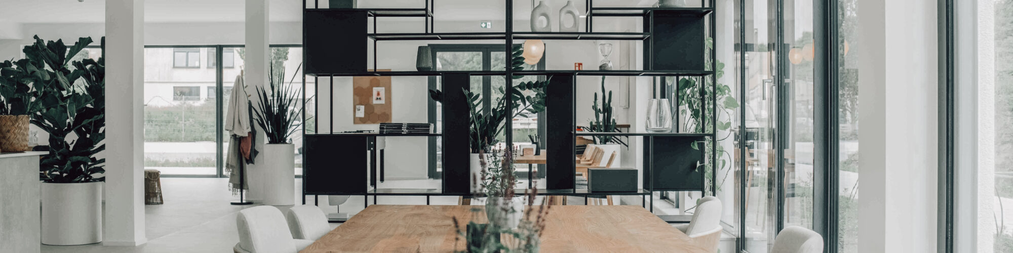 Moderner Coworking Space in Oberhausen mit großen Holztischen, Pflanzen und lichtdurchfluteter Arbeitsatmosphäre.